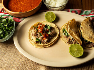 Tacos de cabeza de res con cilantro, cebolla, limon y salsa roja, comida mexicana.