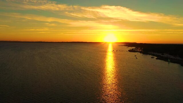 Aerial photo from flying drone of a fascinating nature landscape with dramatic evening sunset sky which reflected in sea water with calm waves. Beautiful scenery with sunset