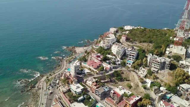 Flying above the coast beach seashore in latin america. Aerial drone dolly shot above mexican resort town along the Pacific shoreline in the state of Sinaloa, Mexico with sea ocean view.