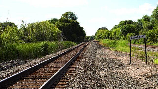 Train Tracks leading off into a lush abandoned and overgrown town.