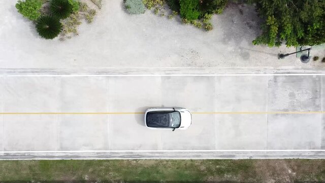 toma a&eacute;rea con dron coche en la furgoneta blanca est&aacute; en la carretera. El dron sigue a un coche que est&aacute; en la carretera entre el &aacute;rbol. Vista superior sobre el coche en movimiento.