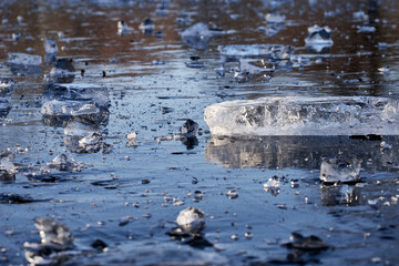 Ice splinters and chunks on a blue frozen river or lake in cold winter, close-up.