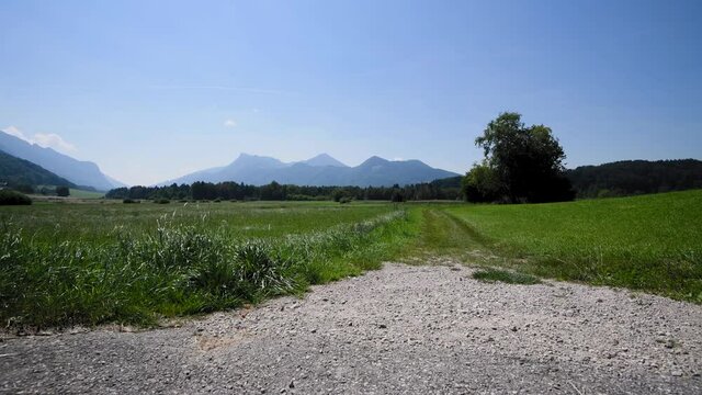 View of the end of a gravel road looking towards a grassy path towards the mountains. Concept of new beginnings.