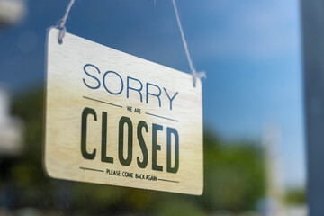 Closed sign broad through the glass of door in cafe., Sorry we're closed sign., Business service...
