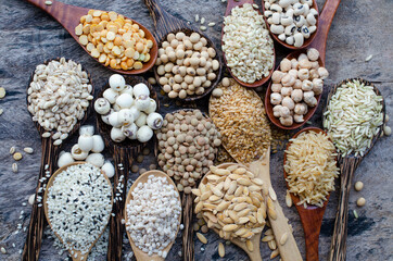 Variety kinds of natural cerean and grain seeds in wooden spoon on grunge background, consisted of rice, mung, sesame, black eye pea, lotus, flax seeds