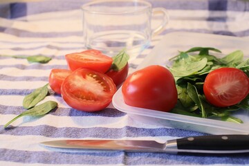 Fresh vegetables: bright red tomatoes, green spinach and cutting knife
