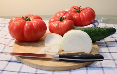 Red large tomatoes, onion white and knife for cutting on wooden board