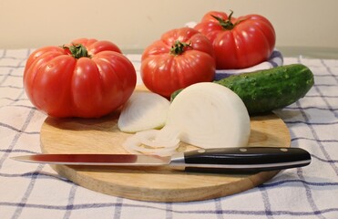 Red large tomatoes, onion white and knife for cutting on wooden board