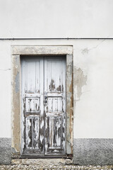 Vintage front door with shubby paint and wall with old weathered damaged house facade in Bergamo, Italy