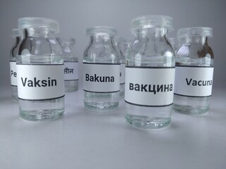 The word vaccine written in different languages ( Russian, Philippines, Indonesian.,Spanish) on vaccine bottles 