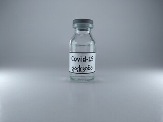 The word COVID 19 vaccine written in Georgian language on a vaccine bottle 