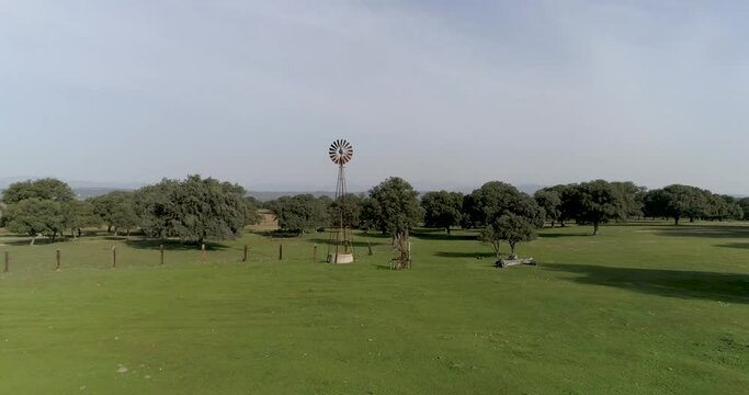 Aerial video Old wind power pump in Spanish farm surrounded by holm oaks