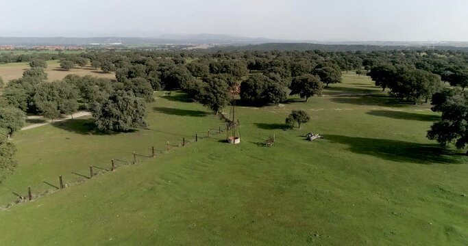 Aerial video Old wind power pump in Spanish farm surrounded by holm oaks