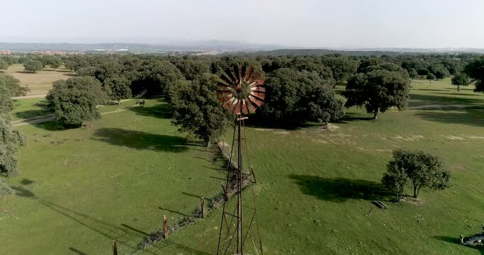Aerial video Old wind power pump in Spanish farm surrounded by holm oaks