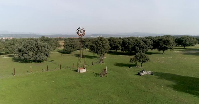 Aerial video Old wind power pump in Spanish farm surrounded by holm oaks