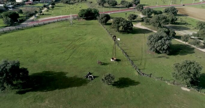 Aerial video Old wind power pump in Spanish farm surrounded by holm oaks