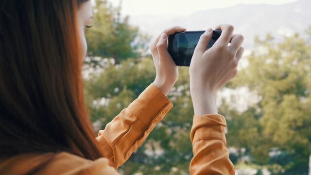 woman with phone in hand takes pictures of nature on camera vacation landscape