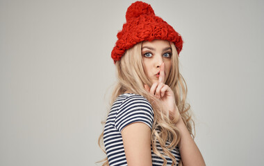 beautiful blonde in a warm hat and striped T-shirt on a light background