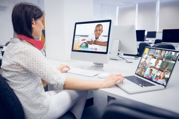 Fototapeta na wymiar Caucasian female teacher using computer and laptop on video call with school children