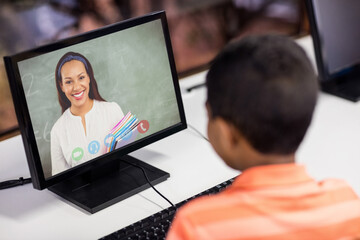 Fototapeta na wymiar Mixed race schoolboy using computer on video call with female teacher