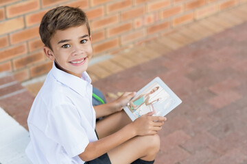 Portrait of smiling caucasian schoolboy using digital tablet on video call with female teacher