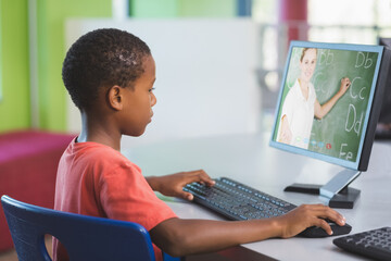 African american schoolboy using computer on video call with female teacher