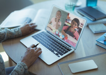 Schoolgirls learning displayed on laptop screen during video call with female teacher