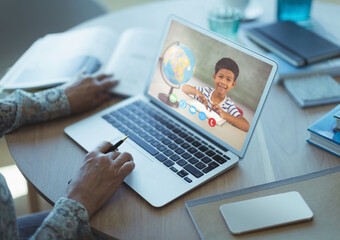 Fototapeta na wymiar Mixed race schoolboy learning displayed on laptop screen during video call with female teacher