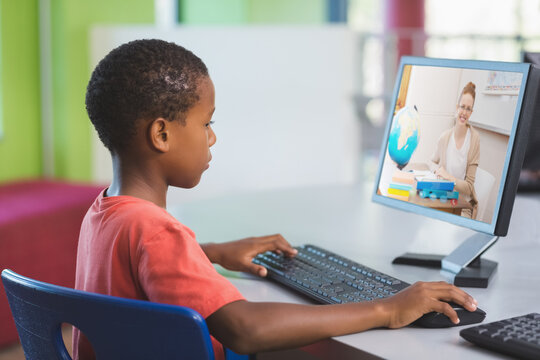 African american schoolboy using computer on video call with female teacher