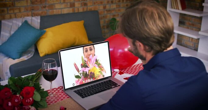 Caucasian couple on a valentines date video call man waving to smiling woman holding bouquet on lapt