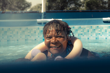 Cheerful smiling African American woman swimming in the pool on a sunny day