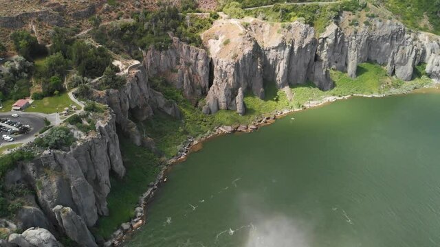 Aerial upward tilt of the cliffs along the Snake River and mist from Shoshone Falls in the foreground near Twin Falls, Idaho.