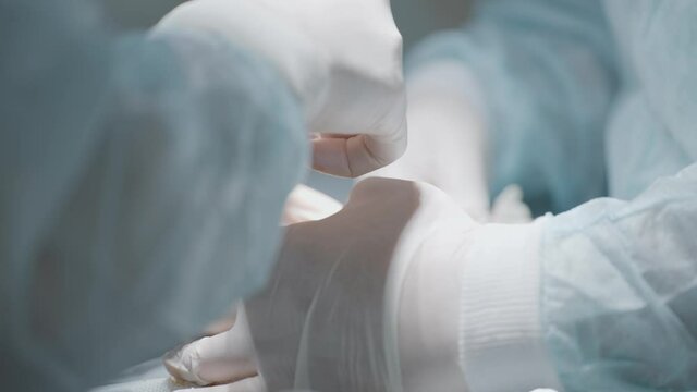 Bloody organ operation. Action. Close-up of two surgeons operating on organ together. Complex operation with large loss of blood. Surgeons make incision on organ and stop bleeding