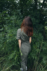 Naklejka premium Woman in forest in green overalls in the park in nature nature travel 