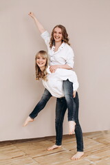 two happy women on a pink background. a woman rolls another on her back. giving a piggyback ride....