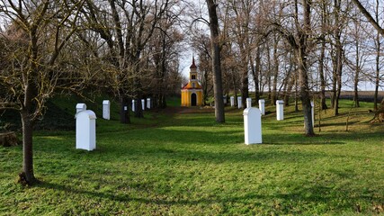 Calvary with small chapel from 1925 nd white Stations of the Cross hidden in circle of naked broadleaf trees, winter season. Location north of Bina village, western Slovakia, central Europe.