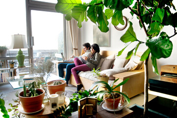 Side view of couple using technologies on sofa