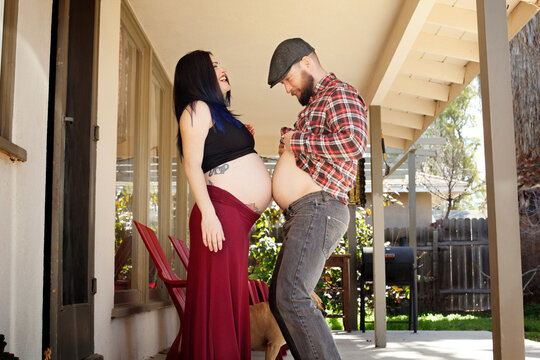Side view of man touching stomach to pregnant woman's belly on porch