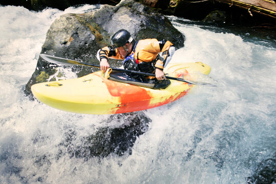 Man kayaking by rocks in river