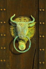 Antique cow door knocker on wooden door