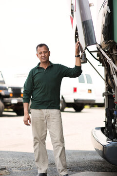 Portrait of mechanic standing by bus against sky