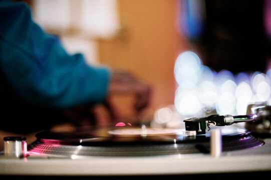 Cropped image of DJ mixing music at record player in nightclub