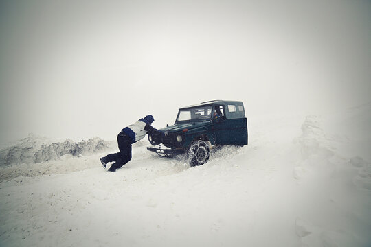 Man pushing car on snow field