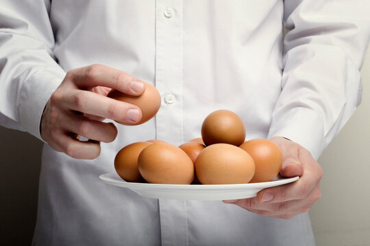 Midsection of chef holding brown eggs in plate - Powered by Adobe