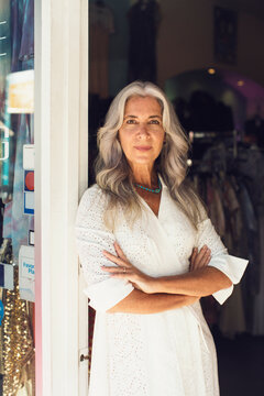 Portrait of female entrepreneur standing arms crossed at the entrance of clothing store