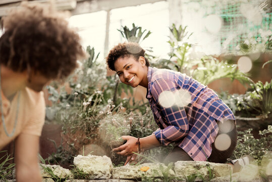 Happy woman looking at friend while gardening in community garden