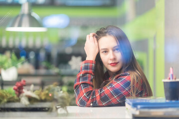 Portrait of a girl behind glass in a cafe. The girl is out of focus.
