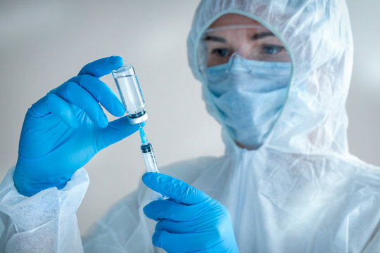 Vaccination COVID-19. concept Doctor in protective medical suit filling syringe with medication