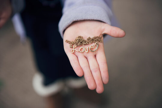 Overhead View Of Hand Holding Locket With Love Text On Street