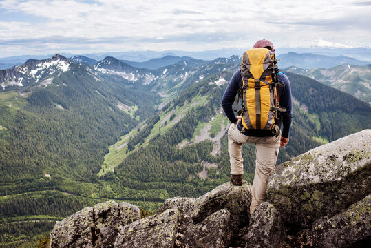 Rear view of hiker standing against mountain range - Powered by Adobe